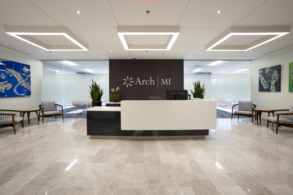 The lobby of the Arch MI office building with a large reception desk in the center, paintings on the wall and a glass wall.